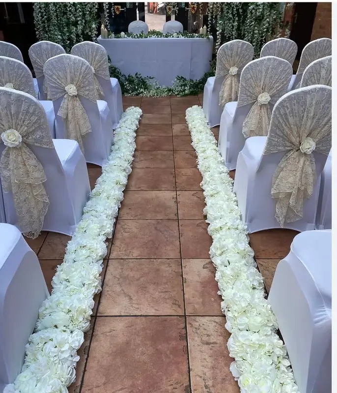 White flower runner laid down a ceremony aisle between chairs in hessian sashes