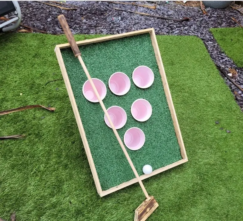 Handmade ball-in-bucket lawn game on artificial grass