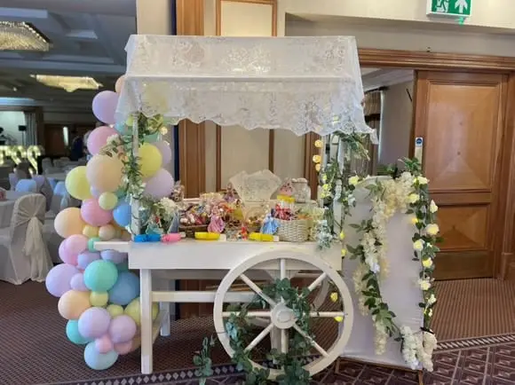 Sweet cart dressed with a pastel balloon garland in a function room