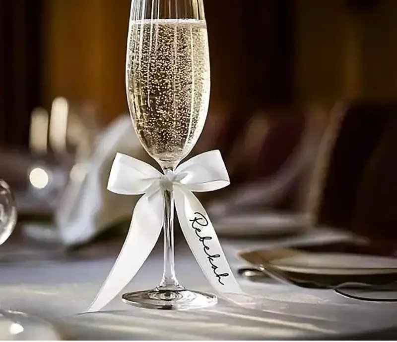 Champagne flute tied with a white ribbon bow and a personalised name