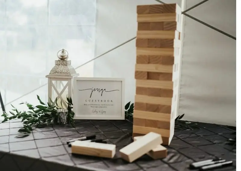 Giant wooden Jenga stack beside a lantern and a signwritten board