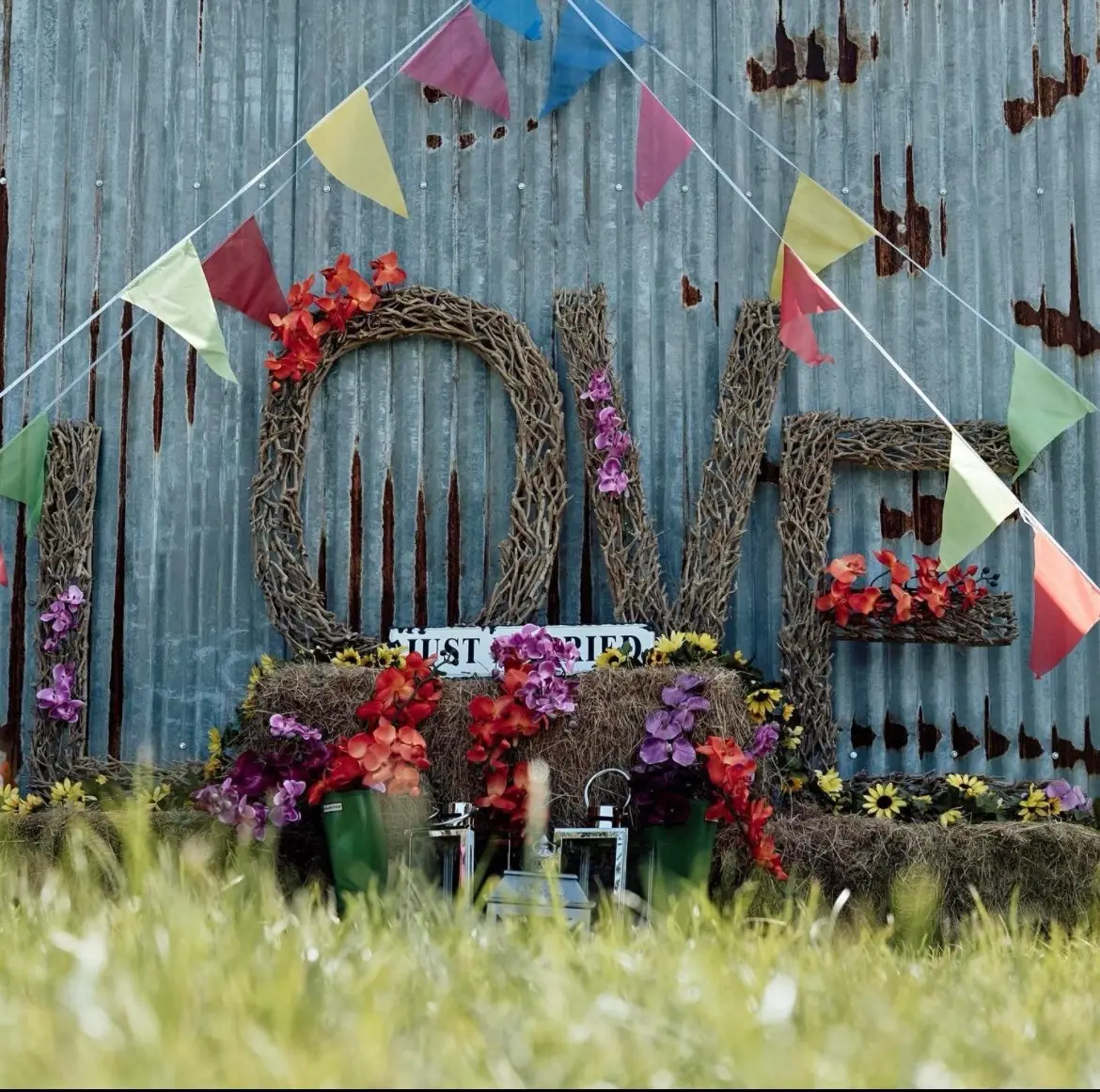 4ft wicker LOVE letters dressed with flowers and bunting against a rustic backdrop
