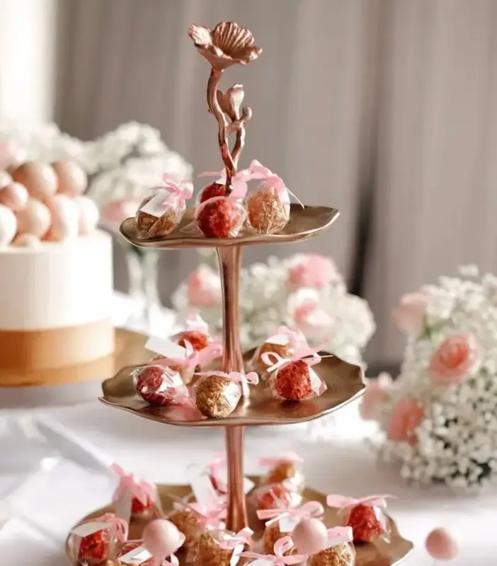 Tiered stand of profiteroles and strawberries beside a white celebration cake
