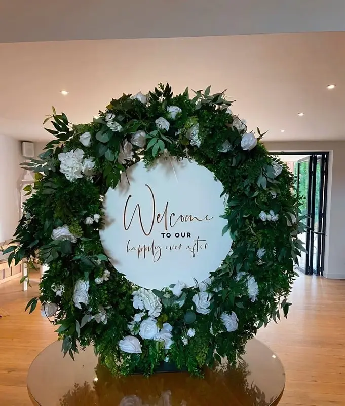 Large foliage and white flower hoop with a Welcome to our happily ever after sign
